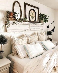 a bed with white sheets, pillows and plants on the headboard in a bedroom