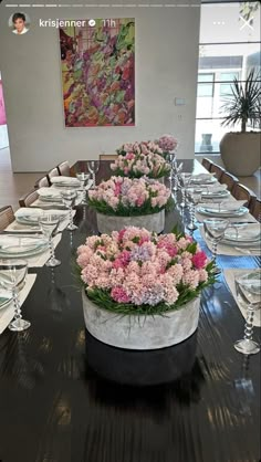 a long table is set with flowers and place settings for the dinner guests to enjoy