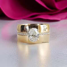 a close up of a wedding ring on a table with pink flowers in the background