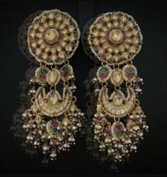 two pairs of gold and green earrings with pearls on the bottom, hanging from each ear