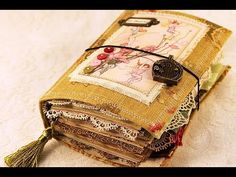 an old book is covered with fabric and lace, decorated with flowers on it's cover