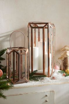 two copper lanterns sitting on top of a mantle next to a christmas tree and other decorations