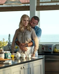 a man and woman standing in a kitchen next to each other with food on the counter