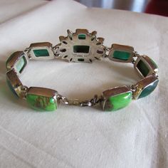 "Sterling silver link bracelet with two amethyst faceted stones and various green stones. There are dark green cushion cut stones, lime green cabs, and two colors of faceted small marquis stones. Some look like peridot. Stamped IB India 925. The center cluster is 1\" tall x 1 1/8\" wide. The length of the bracelet is 8\". Lobster claw clasp. Good condition. Shipped by US mail. LB-1" Modern Green Jewelry With Gemstone Accents, Elegant Green Cabochon Bracelets, Modern Green Multi-stone Jewelry, Green Cabochon Bracelet For Formal Occasions, Vintage Green Bracelet With Natural Stones, Green Cabochon Bracelets For Formal Occasions, Vintage Green Bracelets With Natural Stones, Green Formal Bracelet Jewelry, Formal Green Cabochon Bracelets