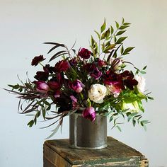 a bunch of flowers that are in a vase on top of an old box,