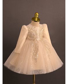 a white dress with sequins on it and a gold headband is sitting on a mannequin