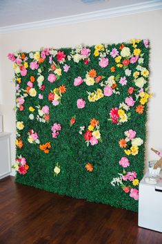 a green wall with flowers on it in the middle of a wood floored room