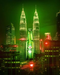 a green beer bottle sitting on top of a tall building in the middle of a city