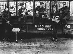 an old black and white photo of some people playing guitars in front of a bus