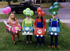 four people dressed up as mario and luigi from mario kart are standing in the grass