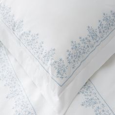 two white pillows with blue embroidery on them