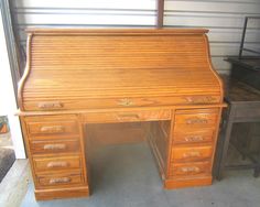 an old fashioned wooden desk with drawers in a garage next to a metal trash can