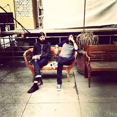 two men sitting on wooden benches in an outdoor area