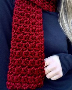 a woman wearing a red crocheted scarf with her hands on her hip and the end of her arm