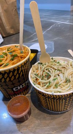 two bowls filled with noodles and sauce on top of a table next to each other