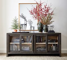 an entertainment center with books, vases and plants on it in front of a mirror