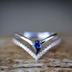 a diamond and blue sapphire ring sitting on top of a rock