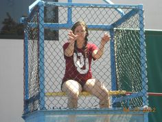 a woman sitting on top of a blue fence