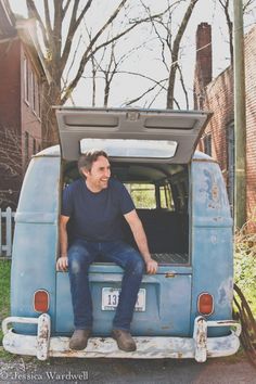 a man sitting in the back of an old blue truck