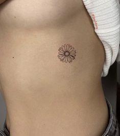 a woman's stomach with a small flower tattoo on the side of her belly