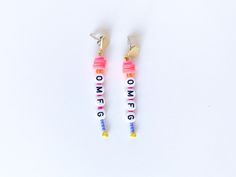 two pairs of earrings with the words one love written on them, sitting next to each other