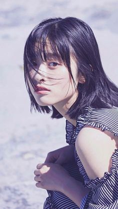 a woman with black hair is posing on the beach