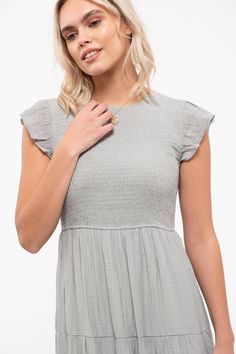 This solid midi-length dress features a smocked body, tiered skirt, and round neckline with a back button and ruffle cap sleeves. Both casual and elegant, this will be a summer staple. Spring Midi Dress With Smocked Bodice And Ruffle Sleeves, Summer Midi Dress With Smocked Bodice And Flutter Sleeves, Casual Dress With Smocked Back And Ruffle Sleeve, Short Sleeve Smocked Dress For Brunch, Chic Smocked Dress With Flutter Sleeves For Spring, Elegant Smocked Dress With Flutter Sleeves For Summer, Casual Midi Dress With Smocked Back And Ruffle Sleeve, Chic Smocked Dress With Flutter Sleeve And Ruffle Hem, Summer Midi Dress With Smocked Bodice And Ruffle Sleeves