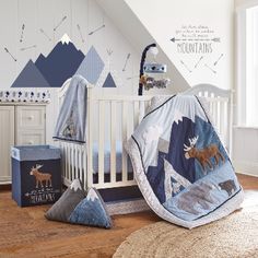 a baby crib with mountains, deer and moose bedding in the corner next to it