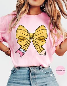 Capture the charm of school days with our "School Days Delight" T-shirt! This adorable tee features a cute bow shaped like a pencil and a retro school bus adorned with hearts on the back. Perfect for teachers, students, or anyone nostalgic for the joys of school, this shirt blends sweet and vintage vibes effortlessly. Made from soft, comfortable fabric, it's ideal for everyday wear or special occasions. Show off your love for learning and bring a touch of cuteness to your wardrobe with this delightful design! Preppy Pink Tops For School, Preppy Pink Top For School, Kawaii Letter Print Tops For School, Trendy Back To School T-shirt For School, Cute Graphic Print Tops For School Events, Pink School Spirit T-shirt For Back To School, Cute Short Sleeve T-shirt For School, Cute Crew Neck Tops For School Events, Casual Pink T-shirt For School