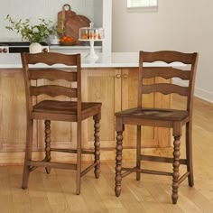 two wooden chairs sitting on top of a hard wood floor next to a kitchen counter