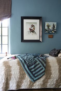 a bedroom with blue walls and pictures on the wall