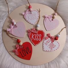 four wooden hearts with the words kiss, love and me on them