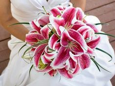 a bride holding a bouquet of pink lilies