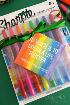 there are many markers and pens in the package on the table next to it is a note that says, teach is to color a life forever