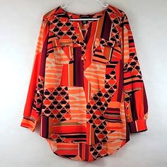 This Valorie Stevens Top Has A Notched V-Neckline And Two Flapped Front Pockets! The Long Sleeves Are Cuffed And Have Elastic Inserts! The Top Has Attractive Geometric Print In Orange, Black, And Brown And Has A High Low Hemline! See Photos For Fabric Content And Care! This Top Seemes To Be Cut Larger, Check Measurements Below! 17" Across Shoulders 31" Shoulder To Bottom Hem (Back) 28" Shoulder To Bottom Hem (Front) 21" Across Armpits Thank You For Shopping!! Orange Workwear Tops For Fall, Orange Tops For Workwear In Fall, Orange Tops For Fall Workwear, Orange Fall Workwear Tops, Trendy Split Neck Fall Blouse, Trendy Split Neck Blouse For Fall, Orange Long Sleeve Blouse For Work, Orange Long Sleeve Top For Layering, Orange Tops For Layering In Fall