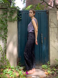 a woman standing in front of a blue door with her hands on her hips and looking off to the side