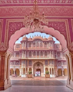 an ornate building with chandelier hanging from it's ceiling and pink walls