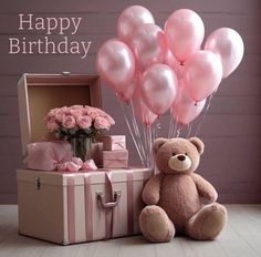 a teddy bear sitting next to a box with pink balloons in it and a bouquet of roses