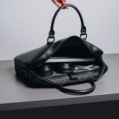 a person holding a black purse on top of a table