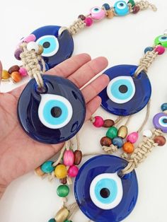 the evil eye necklace is being held by a person's hand with beads around it