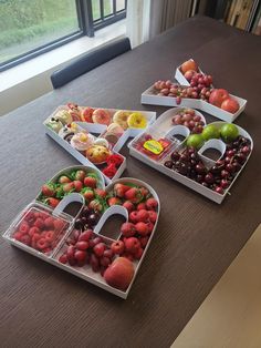 three trays filled with different types of fruit on a table next to a window