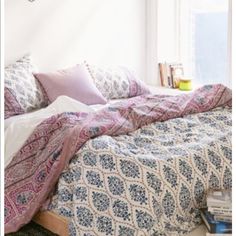 a bed with pink and blue comforter next to a window