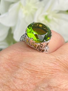 Peridot Sterling Silver RingKing Design#D123 This is a reproduction of a sterling silver Gothic filigree antique ring with a stunning 12 carat green peridot gemstone solitaire. This round cut simulated gem is 15mm in diameter. The inside of the band is marked 925 for sterling silver. Notice the beautiful intricate Gothic claw design of the silver filigree setting. The swirls echo down the band. This large round gemstone sits regally atop the fashionable setting. This stately ring garners attenti Classic Peridot Jewelry With Prong Setting, Classic Peridot Jewelry For May Birthstone, Formal Lime Green Peridot Jewelry, Classic Peridot Solitaire Jewelry, Classic Solitaire Peridot Jewelry, Classic Green Jewelry With Large Stone, Formal Peridot Gemstones For May Birthstone, Classic Green Gemstone With Center Stone, Lime Green Gemstone Jewelry For Formal Occasions