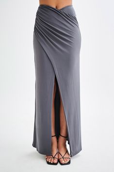 For a summer escapade.The BRONWYN Slinky Ruched Maxi Skirt With Split is a sophisticated and stylish piece designed to make a statement. Featuring a mid-rise fit and a flattering V front, this skirt enhances your natural curves. The centre front split adds a touch of allure, while the ruching at the side seams provides a chic, textured look. Made with stretch fabrication, it ensures comfort and ease of movement. For a complete and stunning outfit, pair this skirt with the Bronwyn Slinky Halter C Ruched Draped Maxi Skirt For Evening, Evening Draped Ruched Maxi Skirt, Chic Draped Fitted Maxi Skirt, Elegant Ruched Skirt For Date Night, Ruched Maxi Skirt For Night Out, Elegant Ruched Bottoms For Date Night, Ruched Draped Maxi Skirt For Party, Draped Ruched Maxi Skirt For Party, Fitted Draped Maxi Skirt For Spring