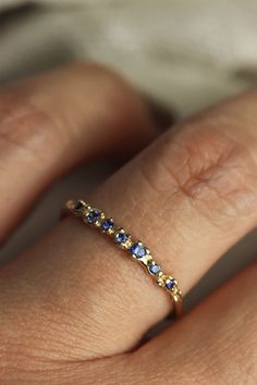 This gorgeous hand-sculpted ring features 7 sparkling blue sapphires set with the daintiest of prongs in an ocean inspired texture. Delicate and comfortable to wear, this solid gold sapphire ring would make the perfect feminine, oceanic wedding band or everyday ring to add to your stack! Details:- Available in 10k yellow or white gold, or 14k, yellow, rose or white gold- Responsibly sourced, natural blue sapphires (.09 total carat weight)- Widest point at the top is approx 1.8mm, bottom of the b Safire Wedding Band, Dainty Birthstone Ring, Gold Sapphire Wedding Band, Wedding Bands With Sapphires, Wedding Band With Colored Stones, Something Blue Ring, Wedding Band Colored Stones, Engagement And Wedding Band Set, Everyday Ring Stack