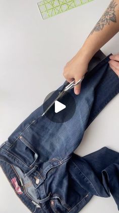 someone is cutting through the back pocket of their jean pants with scissors and paper tape