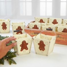 a hand is reaching for some cookies in a wooden box with gingerbreads on it