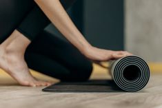 a person kneeling on the floor with a yoga mat in front of them and their feet resting on it