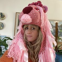 a woman wearing a pink hat and scarf with a cat on it's head