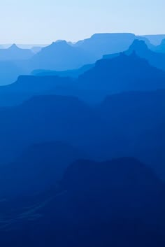 an airplane flying over the top of mountains in the blue sky with no one on it